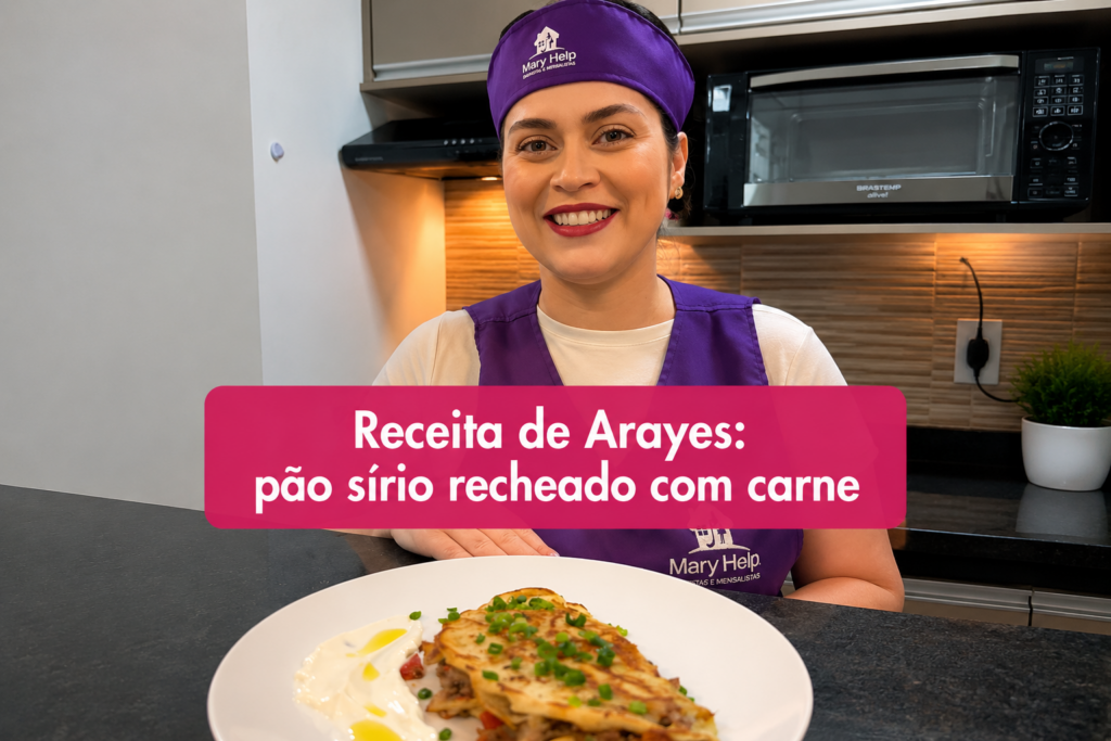 Profissional da Mary Help sorrindo em uma cozinha, ao lado de um prato de Arayes, pão sírio recheado com carne, acompanhado de molho cremoso. A imagem apresenta uma receita de Arayes de carne.