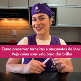 Profissional da Mary Help em uma cozinha, segurando uma vela e apresentando uma dica para preservar torneiras e maçanetas de inox. A imagem destaca o uso da vela para ajudar a manter o brilho das superfícies de inox.