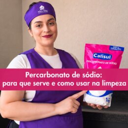 Mulher usando uniforme roxo da Mary Help segura um pacote de percarbonato de sódio Calisul em uma cozinha. Sobre a imagem, há uma caixa rosa com o texto “Percarbonato de sódio: para que serve e como usar na limpeza”.