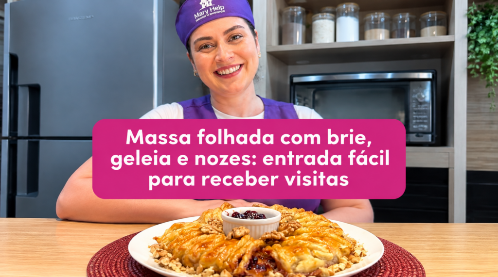 Mulher usando uniforme roxo da Mary Help segura uma torta de massa folhada dourada, recheada com queijo brie, geleia e nozes, em uma cozinha. A imagem traz o texto “Massa folhada com brie, geleia e nozes: entrada fácil para receber visitas”.